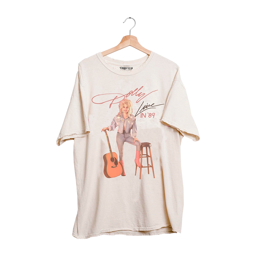 Official Dolly Parton Merchandise. This t-shirt features a vintage photo of Dolly holding an acoustic guitar.